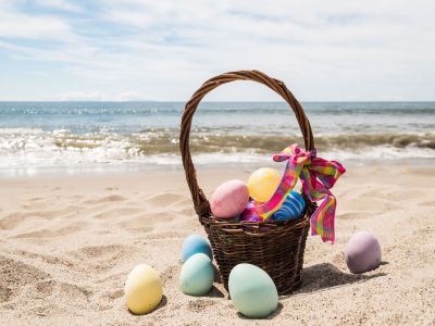 Beach Happy Easter background with basket and color eggs near ocean